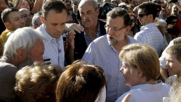 Rajoy y Merkel conversan con varias personas a su llegada a la plaza del Obradoiro