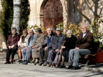 Varios ancianos toman el sol en unos bancos de Olmeda de la Cuesta, Cuenca