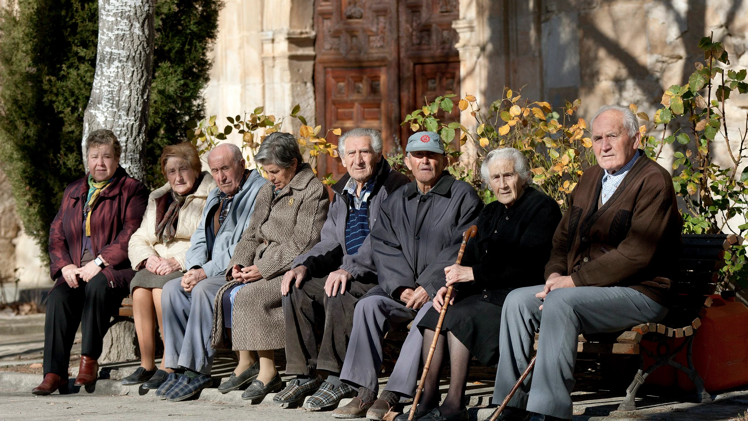 Varios ancianos toman el sol en unos bancos de Olmeda de la Cuesta, Cuenca