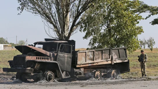 Un soldado ucraniano hace guardia junto a un camión militar calcinado en Mariupol Un soldado ucraniano hace guardia junto a un camión militar calcinado en Mariupol