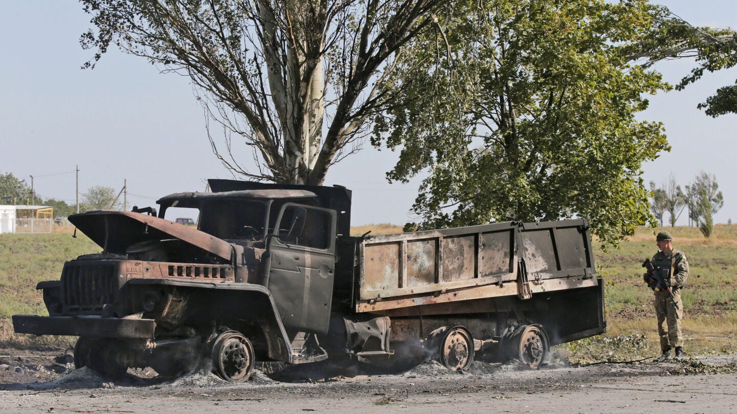 Un soldado ucraniano hace guardia junto a un cami&oacute;n militar calcinado en Mariupol