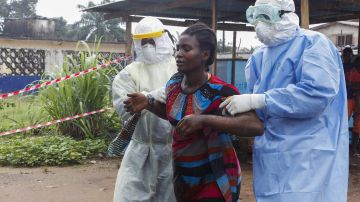 Unos enfermeros escoltan a una mujer supuestamente enferma del ébola