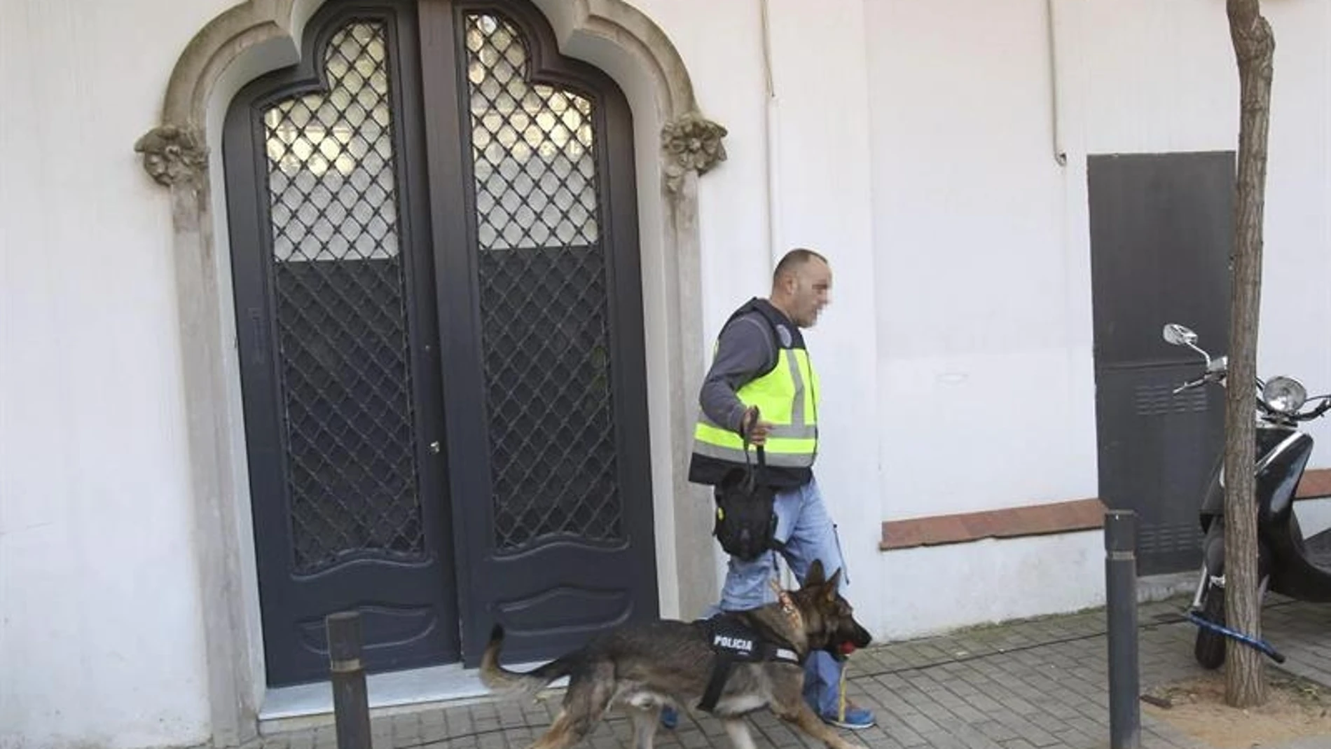 Un policia con un perro sale de la casa de Oleguer Pujol