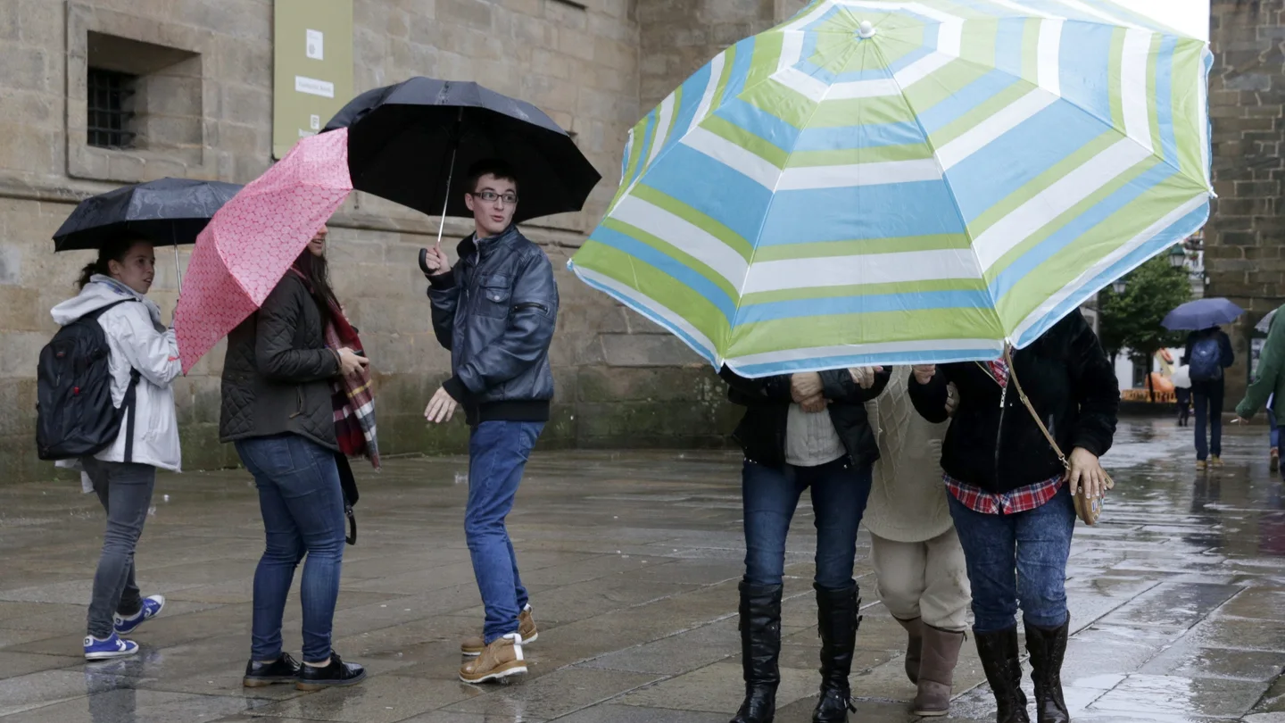 Tres turistas se protegen de la intensa lluvia con una sombrilla en Santiago de Compostela Tres turistas se protegen de la intensa lluvia con una sombrilla en Santiago de Compostela