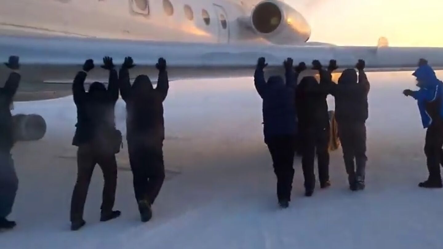 Varios pasajeros empujan su avi&oacute;n en un aeropuerto siberiano para poder despegar
