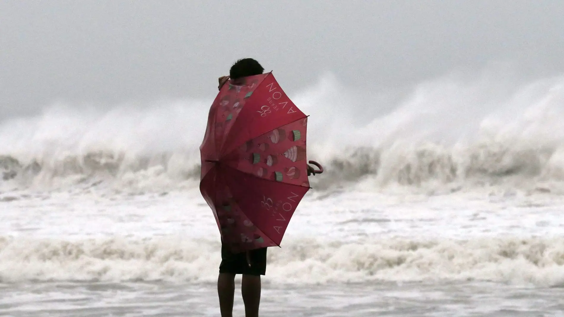 Una mujer se protege del viento del tifó