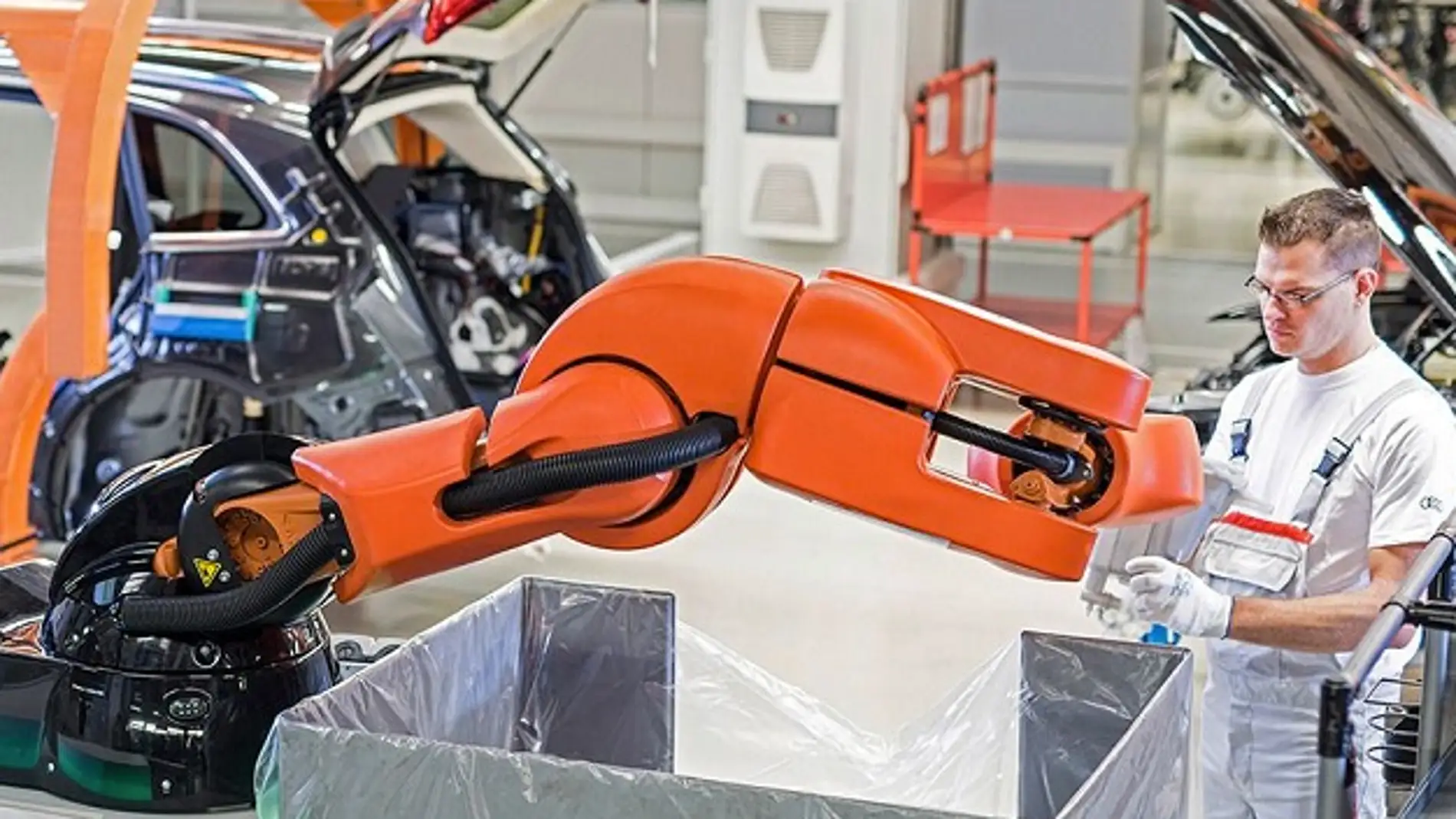 Trabajador y robot construyen coches