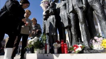 Varias personas depositan flores y velas junto al monumento en memoria de los fallecidos del 11M