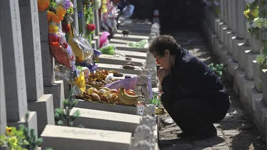 Una mujer reza junto a la tumba de un familiar en un cementerio. Una mujer reza junto a la tumba de un familiar en un cementerio.