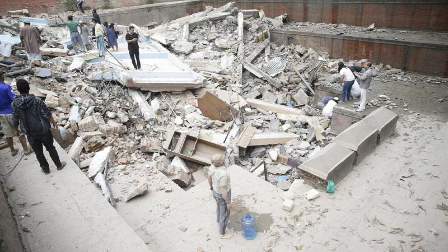 Personas caminando sobre las ruinas de un edificio ca&iacute;do durante el terremoto