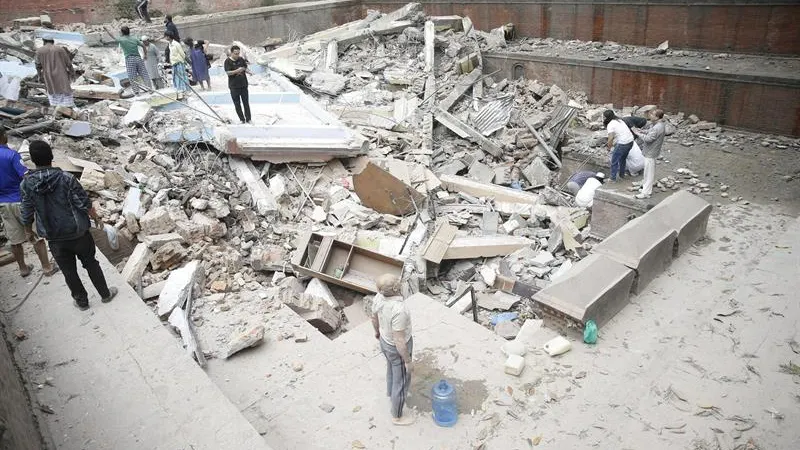 Personas caminando sobre las ruinas de un edificio caído durante el terremoto