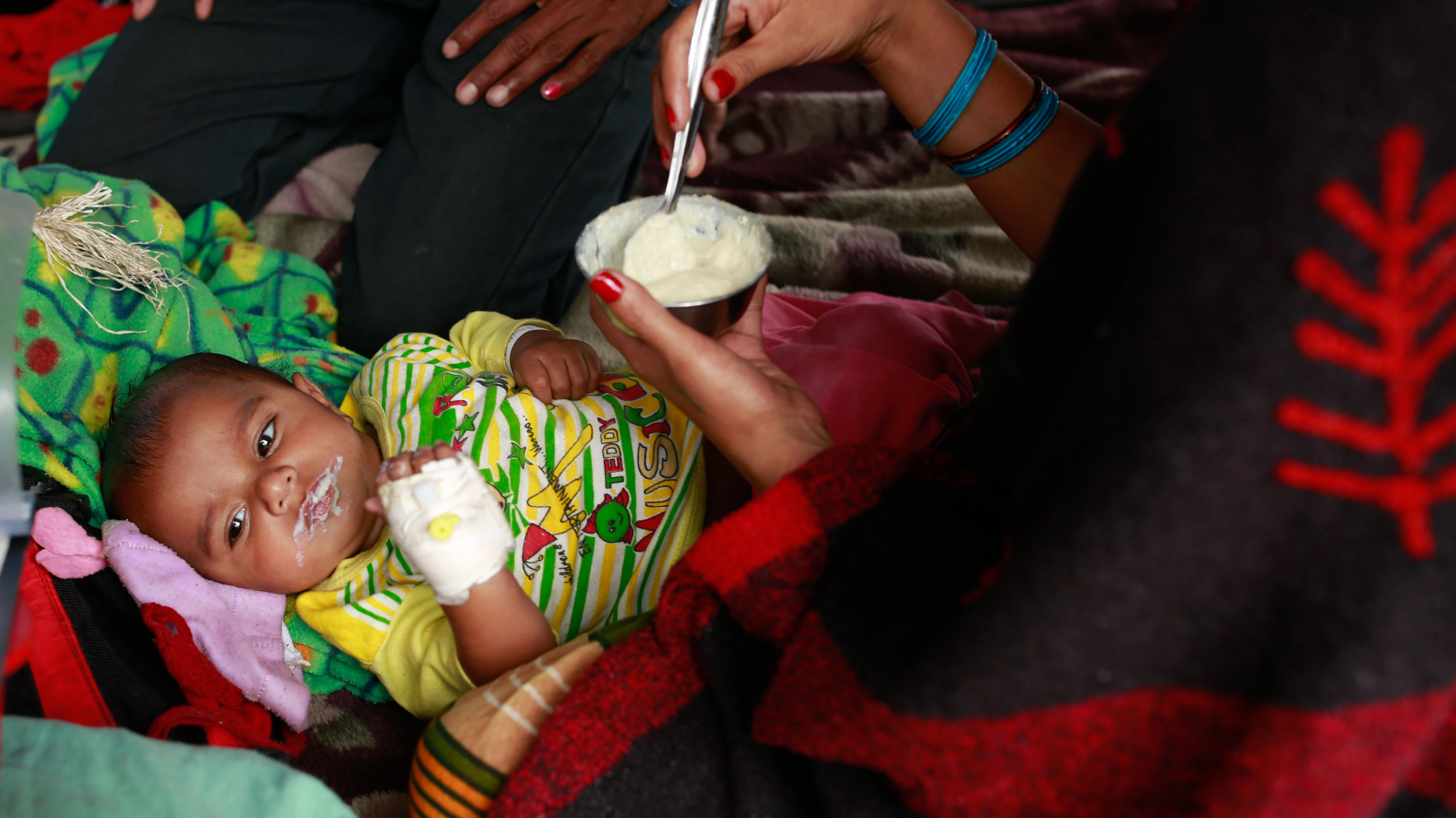 Un bebé es alimentado por su madre en un campamento de afectados en Nepal.