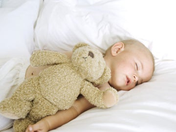Un bebé dormido junto a un osito de peluche. Un bebé dormido junto a un osito de peluche.