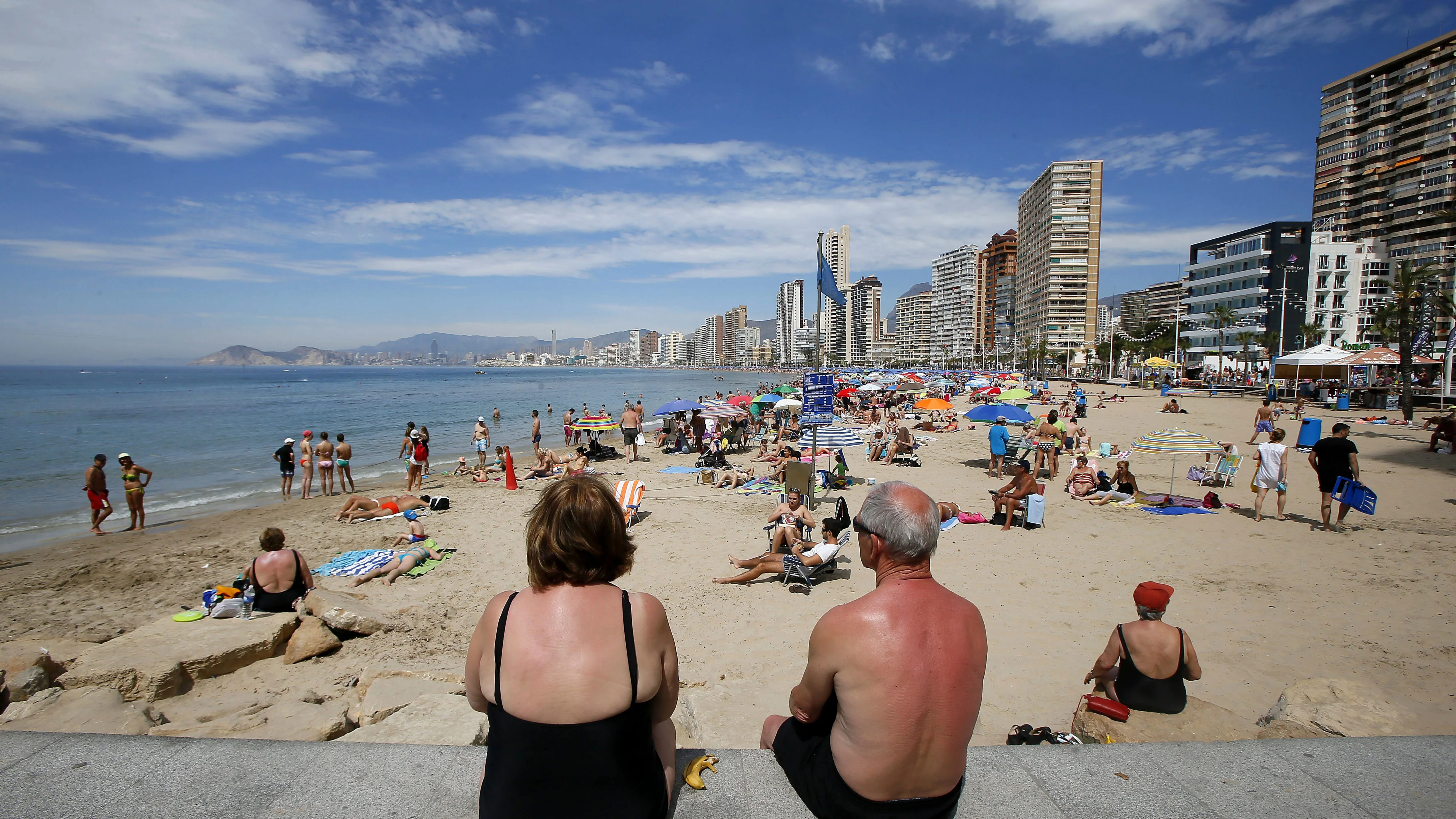 Varios turistas disfrutan de sus vacaciones en la playa.