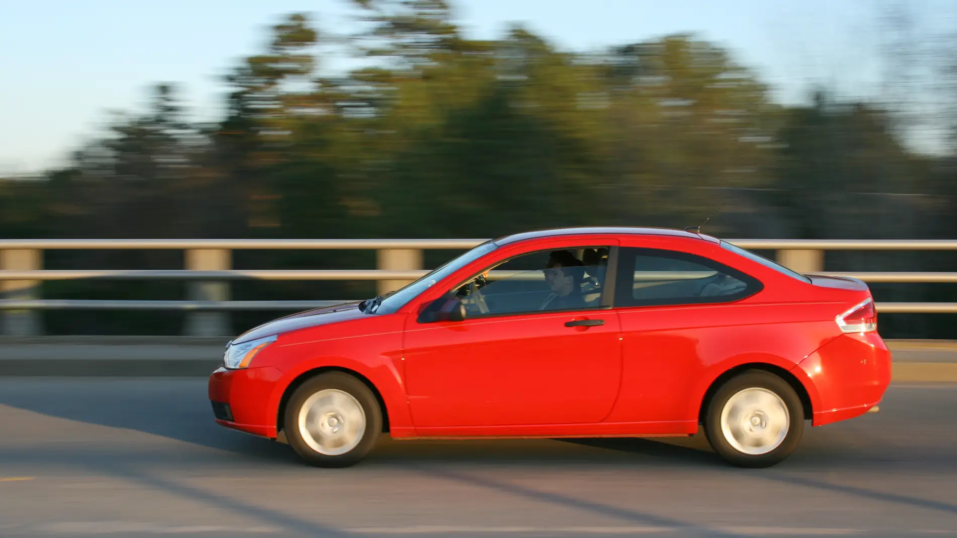 Un coche rojo circula por la carretera (