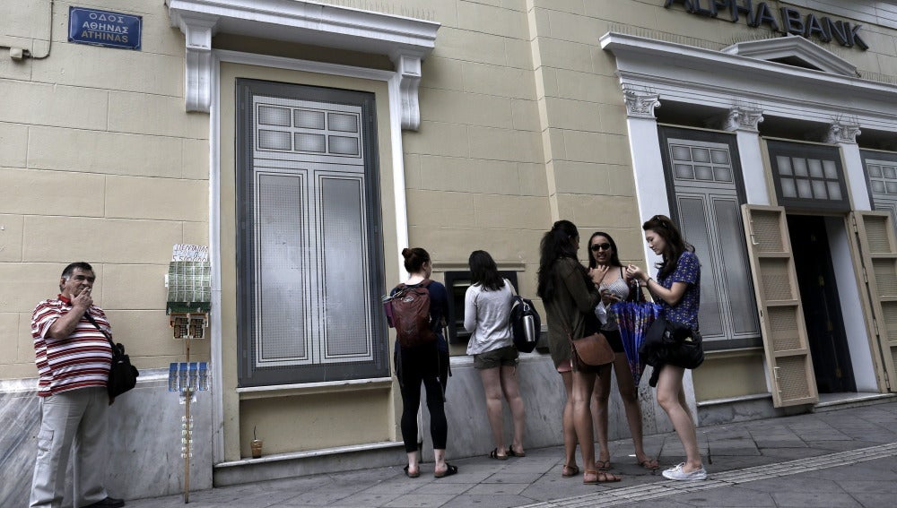 Turistas haciendo cola para sacar dinero de un cajero en Atenas
