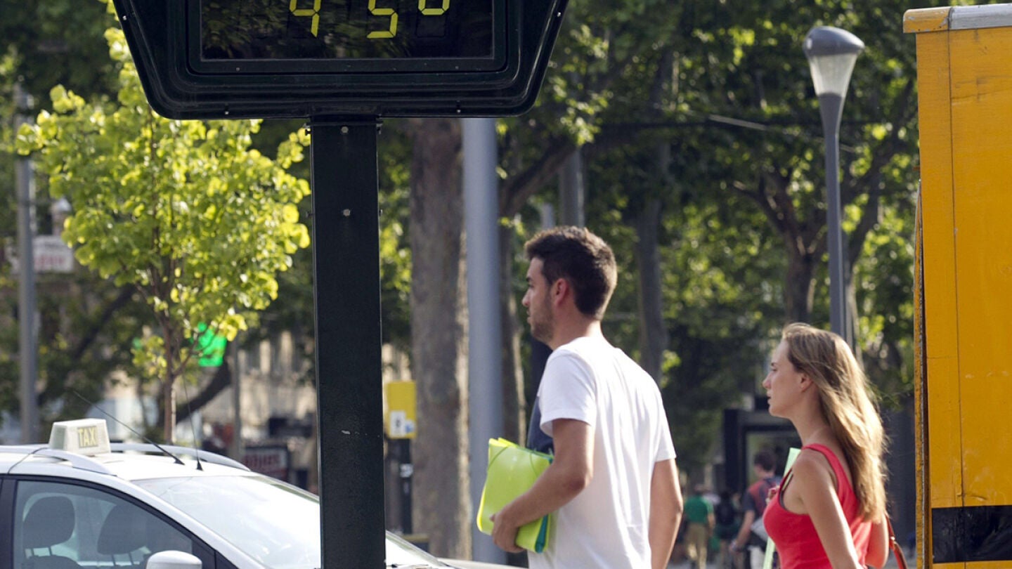 Dos personas pasan por delante de un term&oacute;metro en Zaragoza