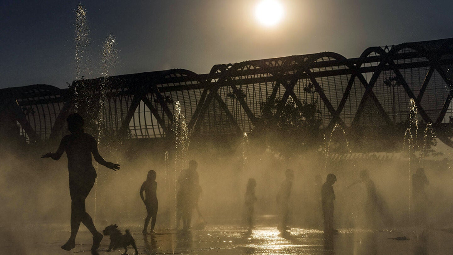 Varias personas se refrescan en la fuente de Madrid R&iacute;o
