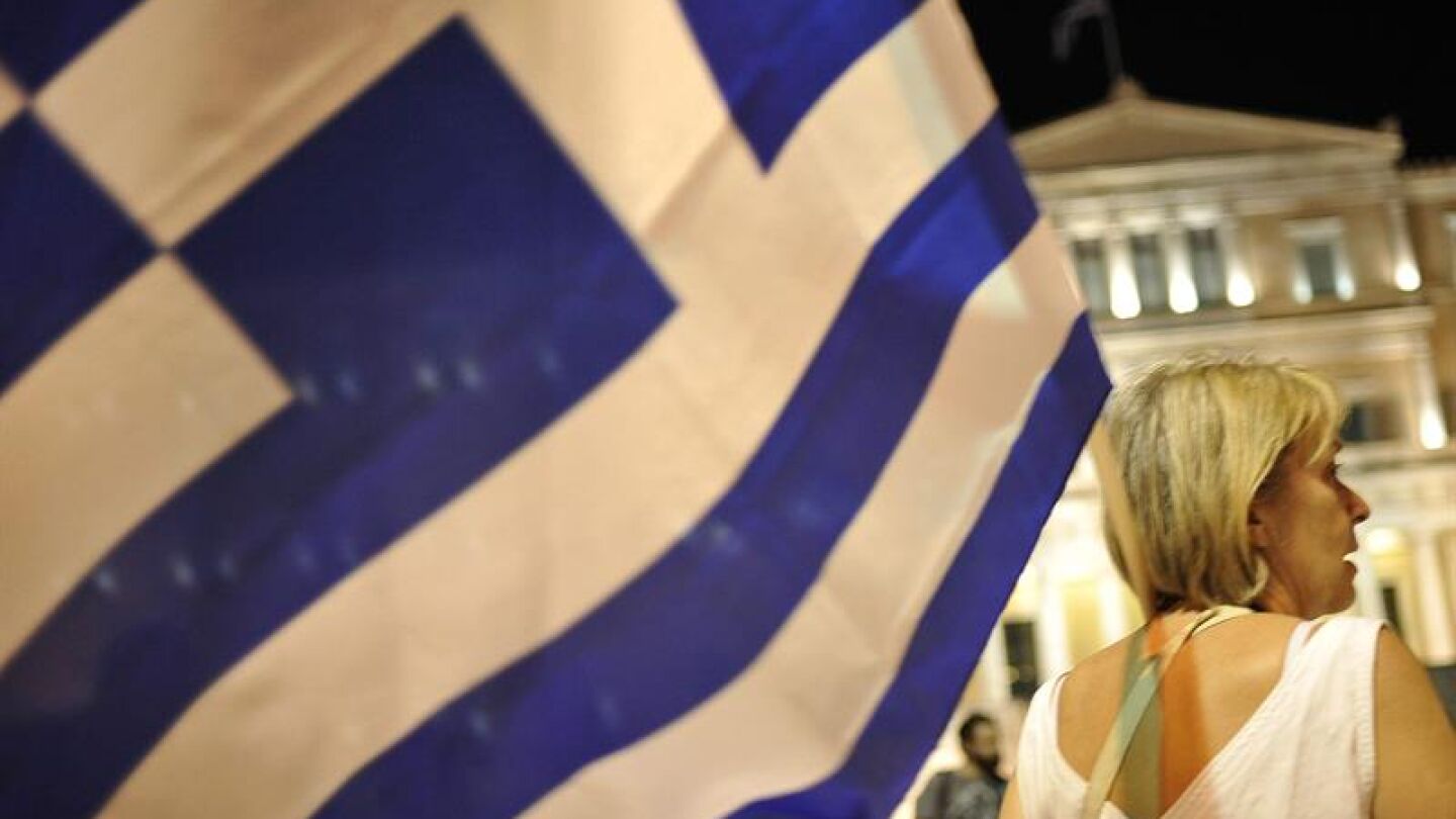 Una manifestante ondea una bandera de Grecia durante una manifestaci&oacute;n