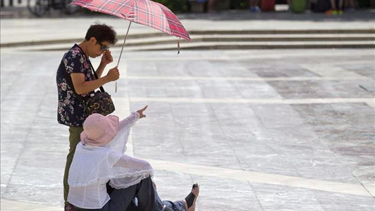 Dos turistas se protegen del calor. Dos turistas se protegen del calor.