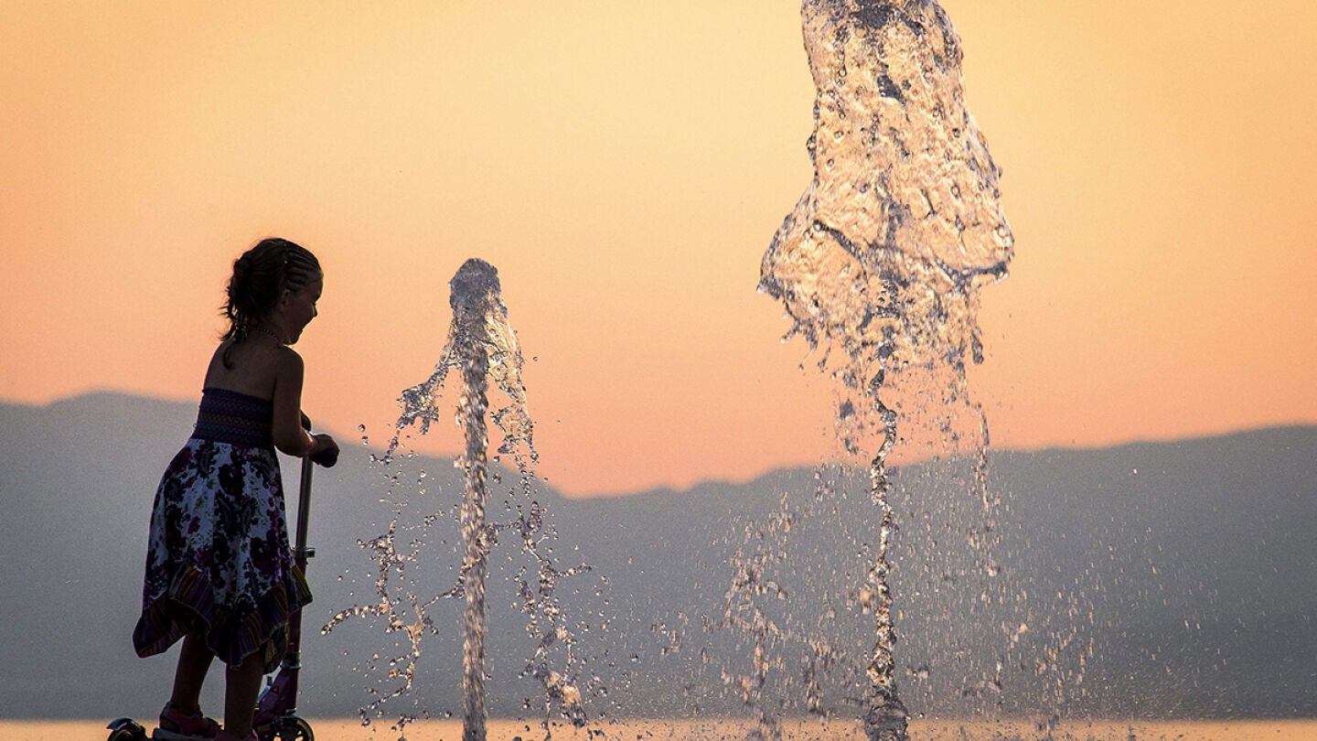 Una ni&ntilde;a se refresca en una fuente para combatir el calor en Francia