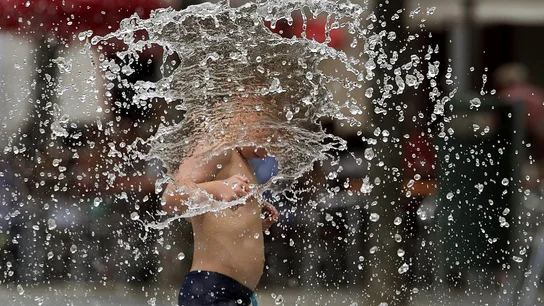 Un niño se refresca en una fuente Un niño se refresca en una fuente
