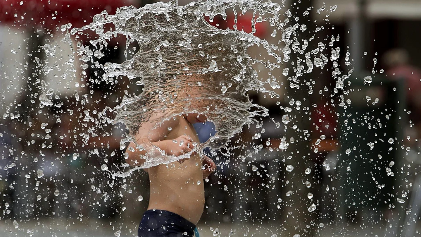 Un niño se refresca en una fuente Un niño se refresca en una fuente