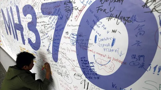 Un hombre escribiendo mensajes en honor a las víctimas del vuelo MH370 de Malaysia Airlines Un hombre escribiendo mensajes en honor a las víctimas del vuelo MH370 de Malaysia Airlines