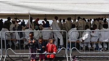 Inmigrantes bajo una carpa de Cruz Roja tras llegar a Salerno, Italia