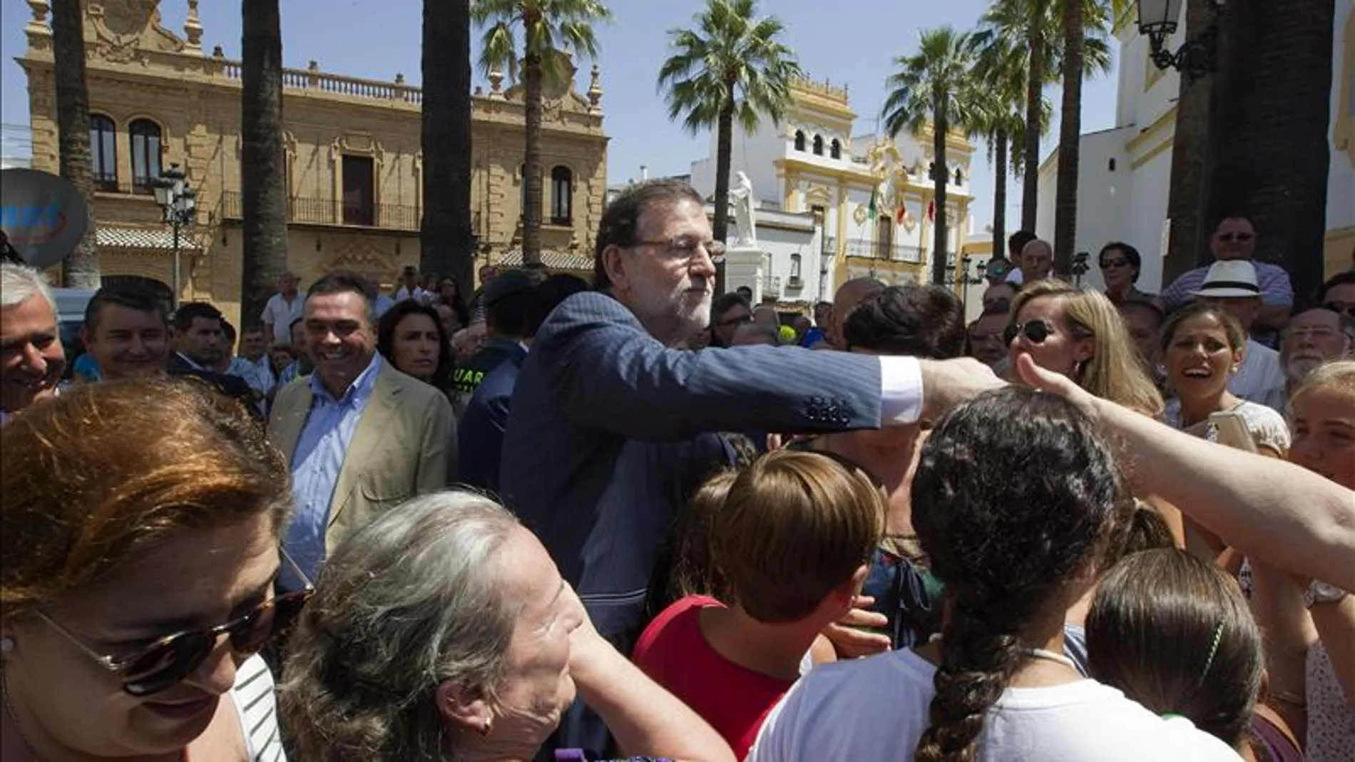 El presidente del Gobierno y del Partido Popular, Mariano Rajoy (c), saluda a varios vecinos de La Palma del Condado (Huelva),