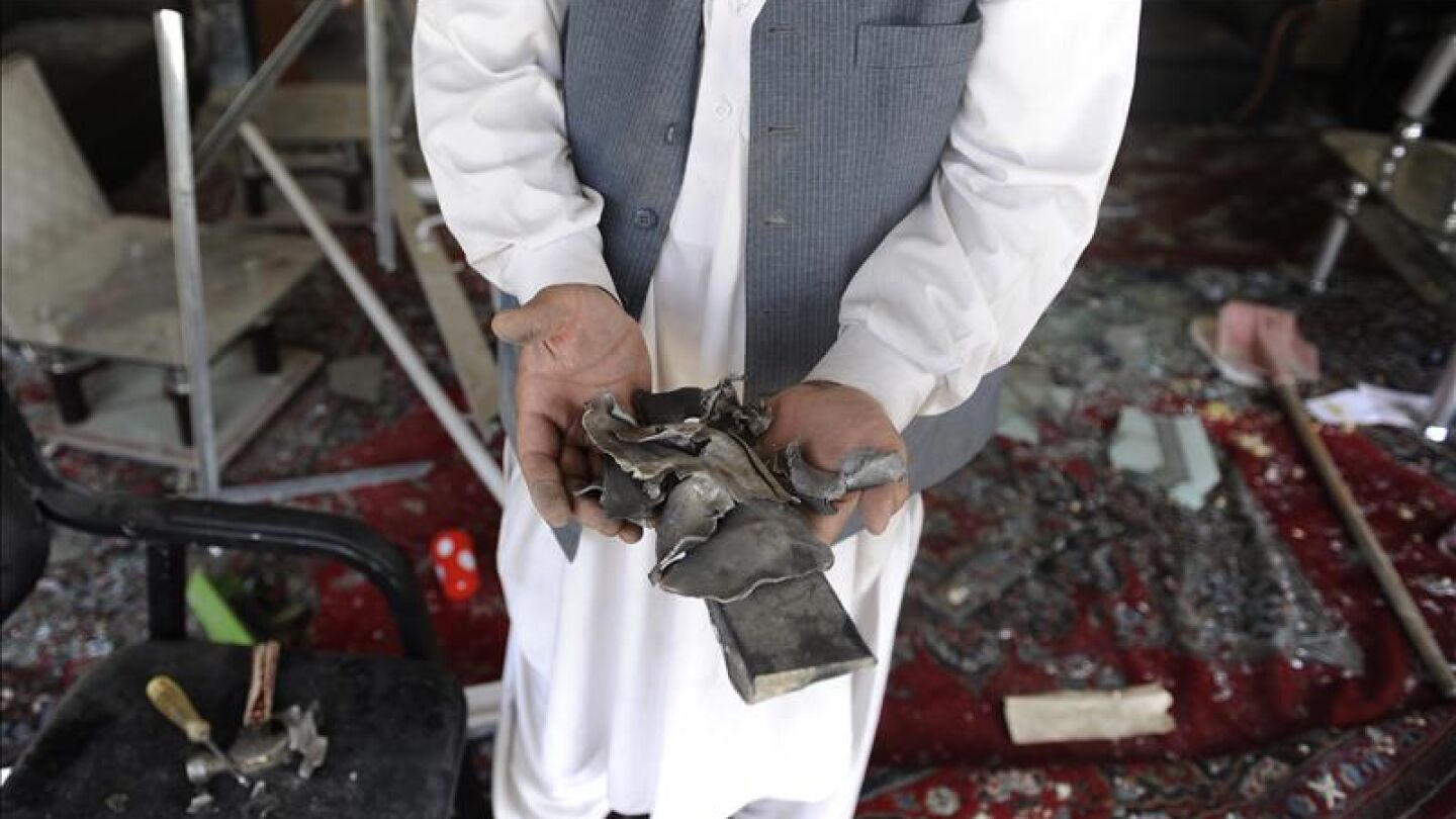 Un hombre muestra objetos rotos en el lugar de la explosi&oacute;n de una bomba en Kabul (Afganist&aacute;n)
