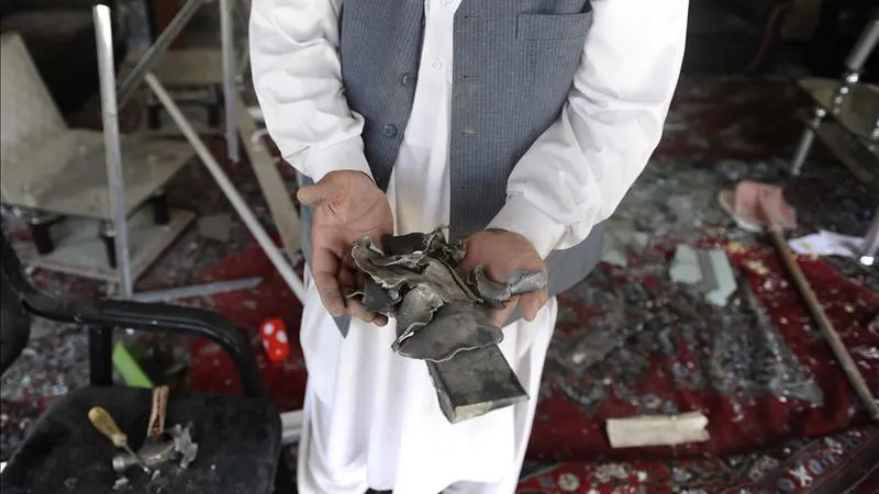 Un hombre muestra objetos rotos en el lugar de la explosión de una bomba en Kabul (Afganistán)