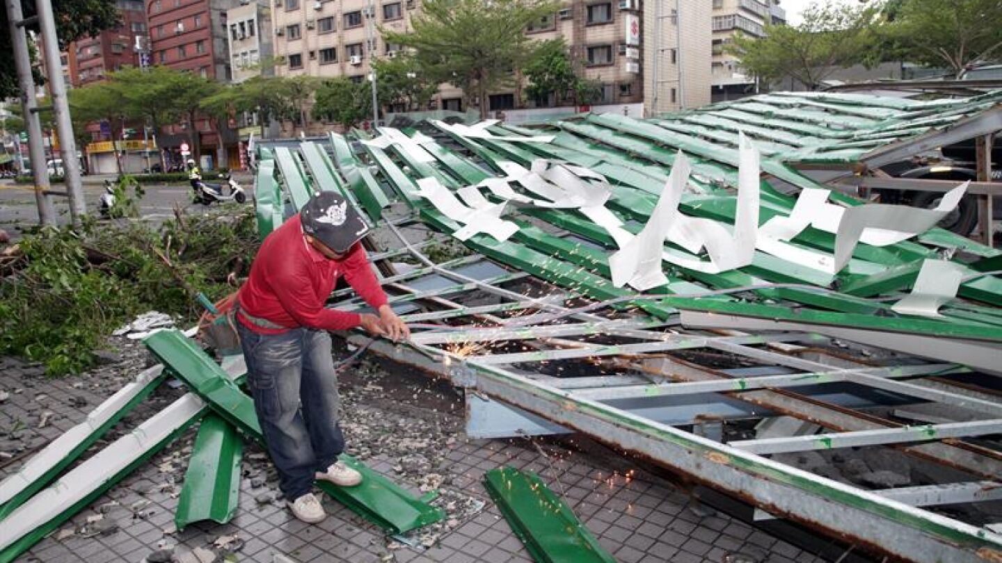 Un trabajador taiwan&eacute;s corta una estructura derribada por el tif&oacute;n Soudelor