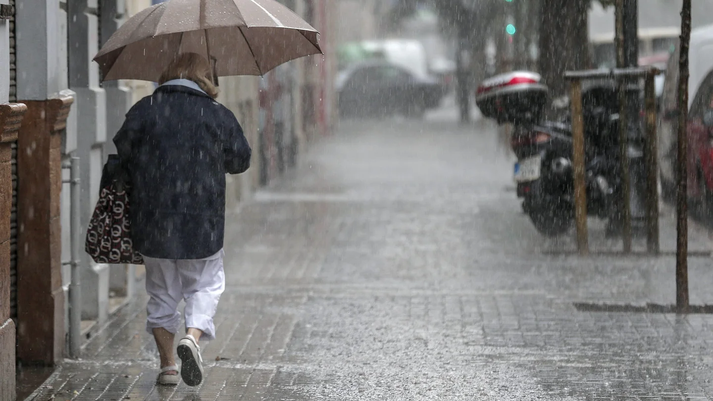 Una señora se refugia de la lluvia Una señora se refugia de la lluvia