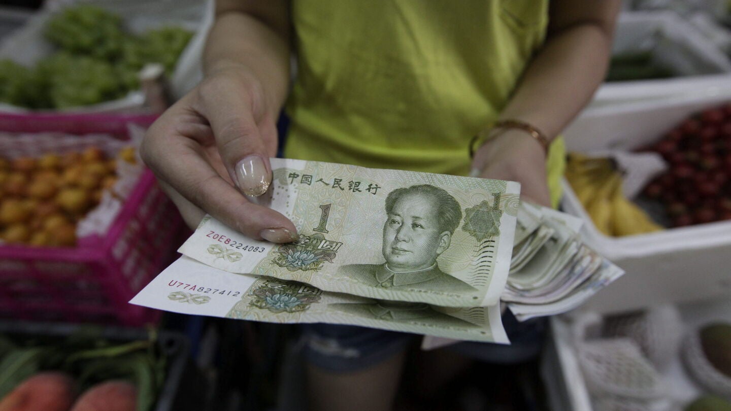 Una mujer muestra billetes de yuan en Pek&iacute;n