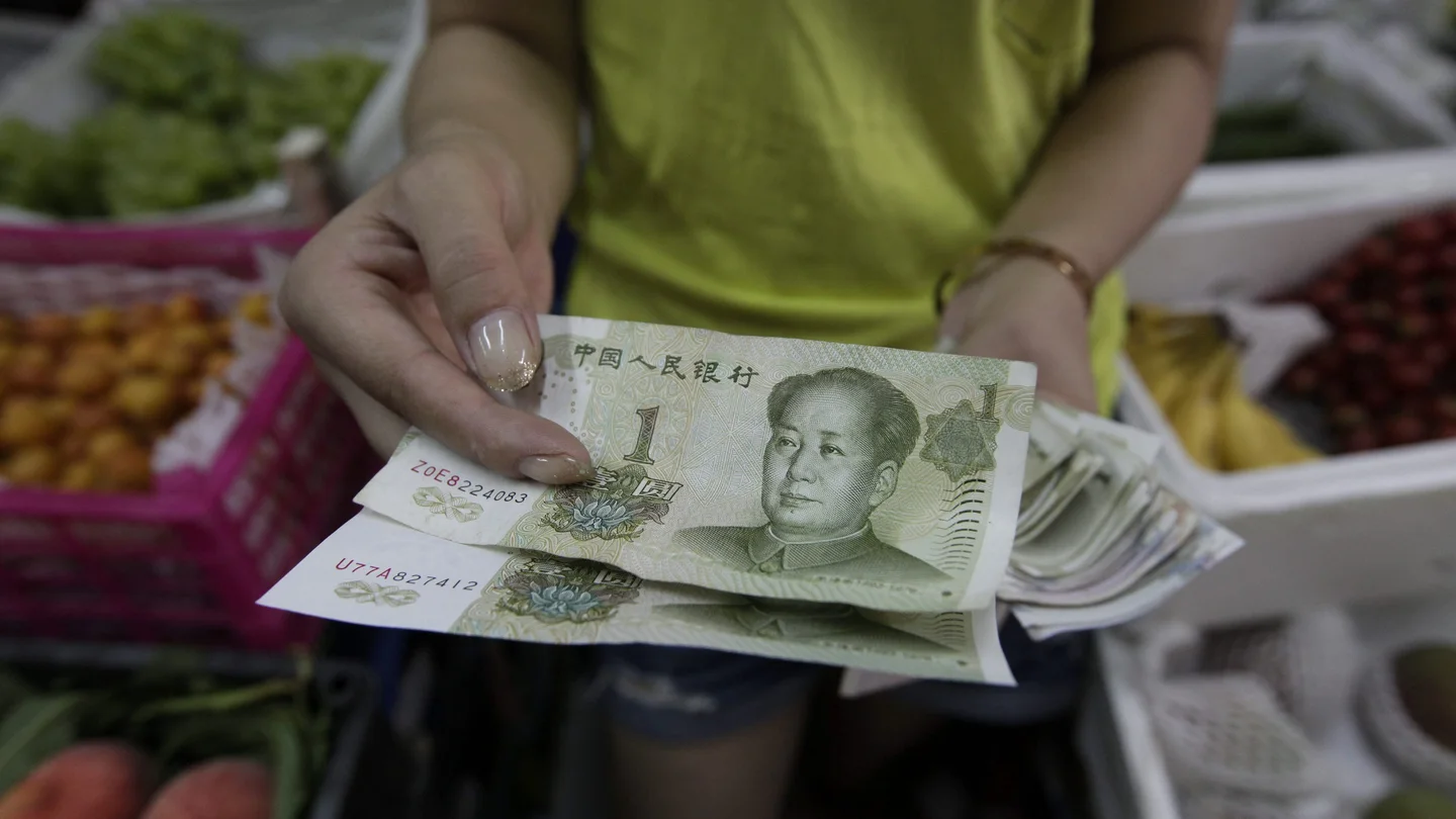 Una mujer muestra billetes de yuan en Pekín Una mujer muestra billetes de yuan en Pekín