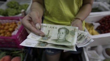 Una mujer muestra billetes de yuan en Pekín