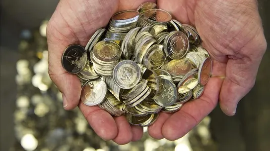 Un hombre sostiene varias monedas de euro Un hombre sostiene varias monedas de euro