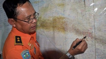 Un oficial de rescate indonesio muestra en un mapa la zona en la que se ha localizado el avión 