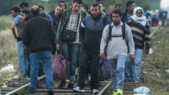 Inmigrantes caminan sobre las vías de un tren Inmigrantes caminan sobre las vías de un tren