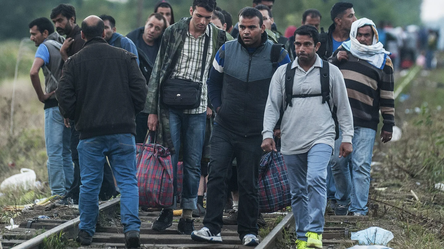 Inmigrantes caminan sobre las vías de un tren Inmigrantes caminan sobre las vías de un tren
