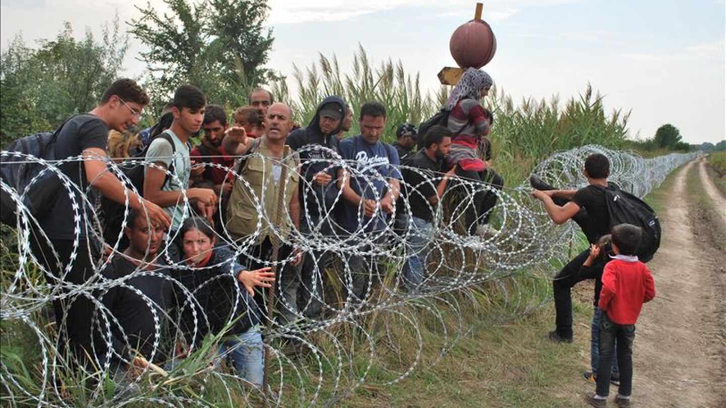 Varios refugiados sirios intentando saltar la alambrada de la frontera entre Hungr&iacute;a y Serbia