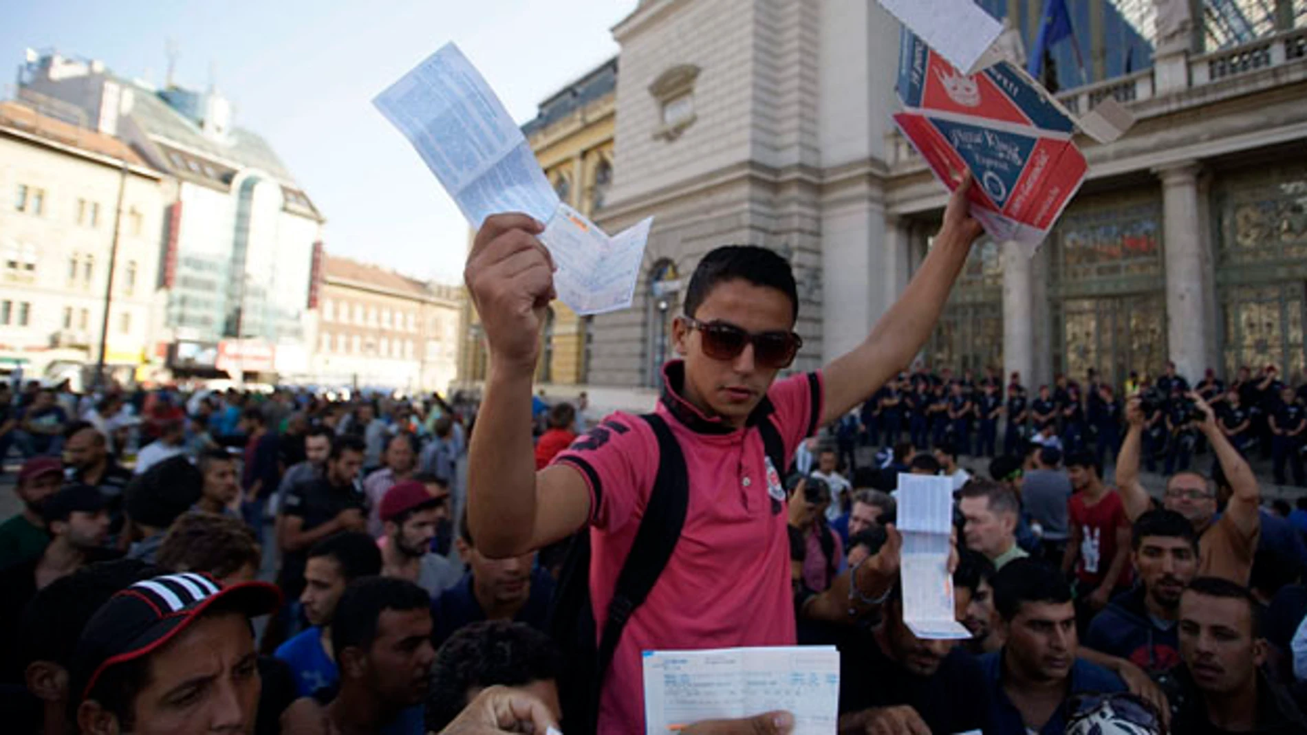 Inmigrantes muestran sus billetes de tren a las puertas de la estación de Keleti 