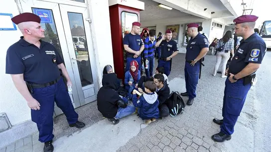 Policías observan a un grupo de refugiados durante el reparto de alimentos Policías observan a un grupo de refugiados durante el reparto de alimentos