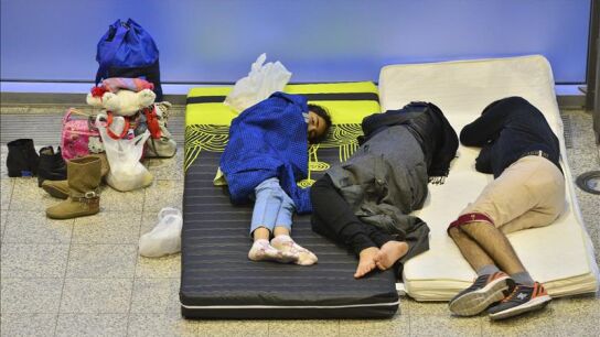 Una familia de refugiados descansa sobre dos colchones en el recinto ferial de Messe Erfurt