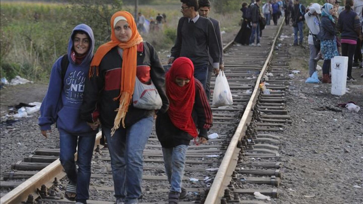 Inmigrantes caminan junto a una l&iacute;nea de tren cerca de la frontera h&uacute;ngara