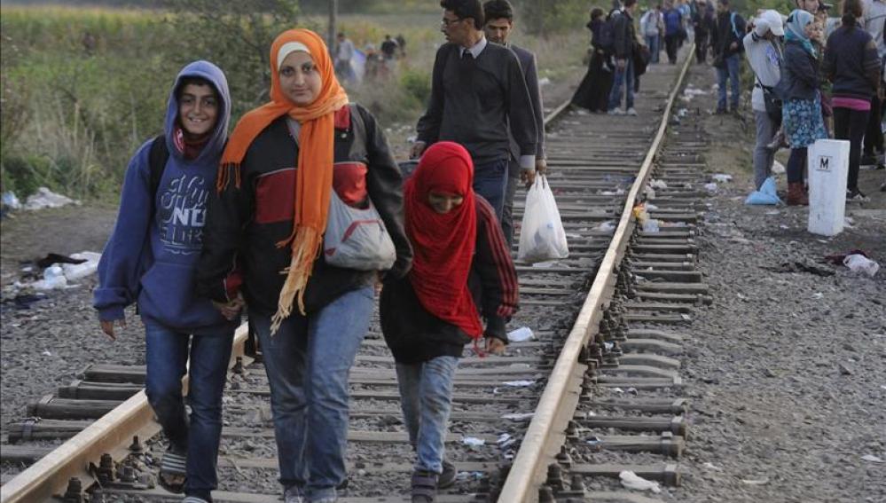 Inmigrantes caminan junto a una línea de tren cerca de la frontera húngara