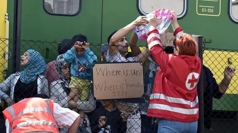 Miembros de la Cruz Roja reparten botellas de agua a los refugiados