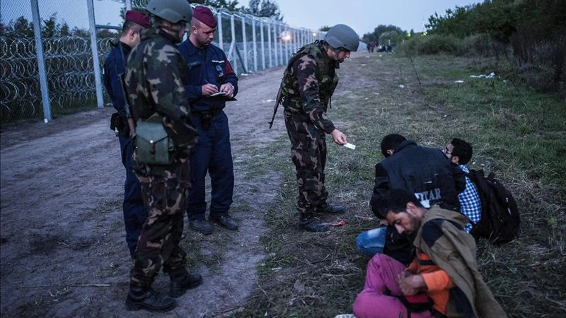 Policías y soldados comprueban la documentación de varios refugiados en la frontera entre Serbia y Hungría