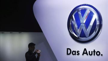 Un hombre frente al logotipo del fabricante alemán Volkswagen